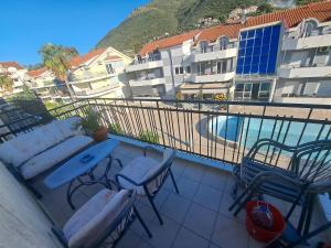 a balcony with a couch and chairs and a swimming pool at Nearby PORTONOVI-Norwegian-village DUPLEX in Đenovići