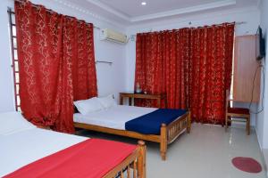 a bedroom with two beds and red curtains at Sun Shine Resort & Spa in Kovalam