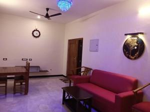 a living room with a red couch and a table at Tamil Homestay in Thanjāvūr