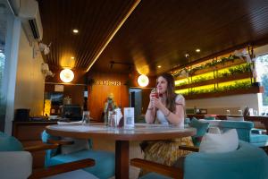 a woman sitting at a table in a restaurant at B Town Resort Near Infopark Kakkanad in Kakkanad