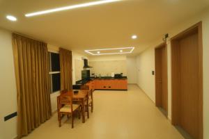a kitchen with a table and chairs in a room at Arunaragha in Mysore