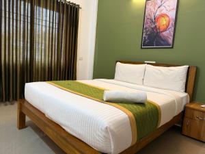 a bedroom with a large bed with a green wall at Hotel serenity in Cochin