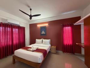 a bedroom with a large bed with red curtains at Hotel serenity in Cochin