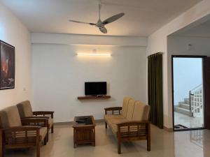a living room with a couch and chairs and a tv at Hotel serenity in Cochin
