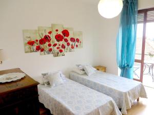 2 Betten in einem Zimmer mit roten Blumen an der Wand in der Unterkunft Giuse in Verbania