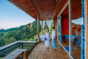 a bride and groom standing on the balcony of a house at Mon Ngo misty haven B1 in Ban Mae Ta Man