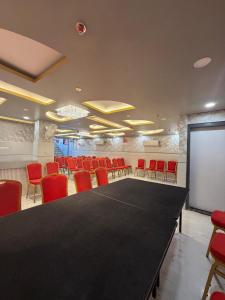 a conference room with a black table and red chairs at Hotel Aveda Paradise in Varanasi