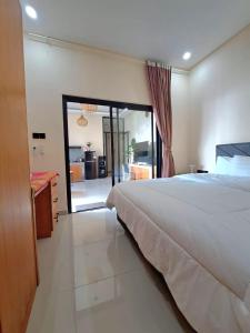 a bedroom with a large bed and a sliding glass door at Best Value Room Sanur Walk to Beach - NVB in Sanur