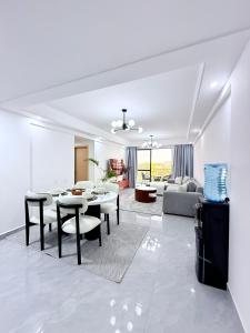 a white living room with a table and chairs at Pearl Luxe Homes at Orchid Residency - Spacious 2BR in Westlands With Pool, Gym, Rooftop views & breakfast café in Nairobi
