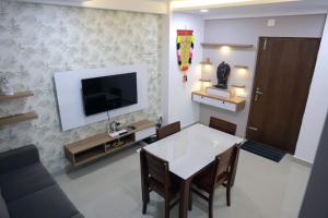 a living room with a table and a tv on a wall at Vaiga Heavens - 1 BHK Apartment, 500 m to temple in Guruvāyūr