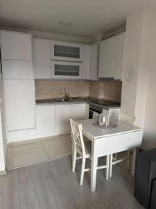 a kitchen with white cabinets and a table and chairs at White Horizon Apartment in Teslić