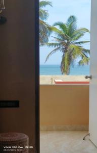 a door to a room with a view of a palm tree at The K Inn Wavefront in Mahabalipuram