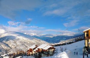 エムにあるVillage Vacances La Lauzièreの雪に覆われた山々と建物のあるスキー場
