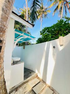 a white fence with a tree and palm trees at 101 Sosi in Kudafari