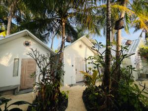 a white house with palm trees in front of it at 101 Sosi in Kudafari
