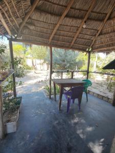 a table and a chair under a wooden roof at Chez Émile in Anakao
