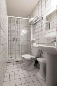 a bathroom with a toilet and a shower and a sink at Hotel des Carmes in Aurillac