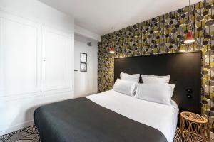 a bedroom with a large bed with a black headboard at Hotel des Carmes in Aurillac