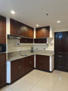 a large kitchen with wooden cabinets and a sink at Uptown Condotel in Bulwa