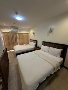a bedroom with two beds with white sheets at Uptown Condotel in Bulwa