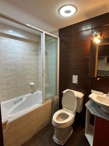 a bathroom with a toilet and a tub and a sink at Uptown Condotel in Bulwa +7 photos