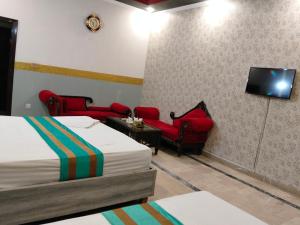 a hotel room with two beds and two chairs and a tv at Moon Palace Hotel Lahore in Lahore +25 photos