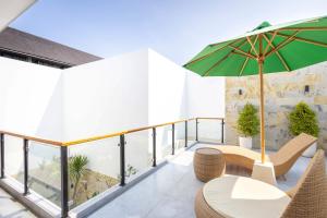 a balcony with a table and a green umbrella at Villa Surga in Denpasar