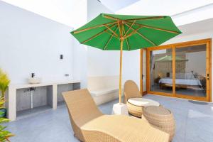 a living room with a green umbrella and chairs and a bed at Villa Surga in Denpasar