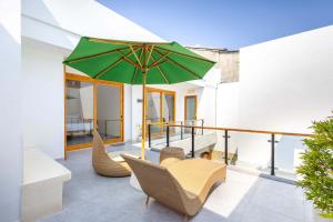 a patio with a green umbrella and chairs at Villa Surga in Denpasar
