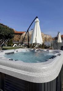 an outdoor hot tub with an umbrella and an umbrella at Къща за гости ЕМА in Vetren Dol