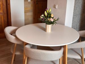 a white table with a vase of flowers on it at Fiskerhytte - Meine Fischerhütte in Börgerende-Rethwisch