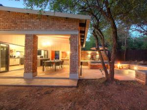 a brick house with a patio with a tree at Spoorzicht in Marloth Park