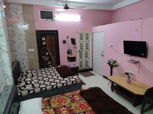 a bedroom with two beds and a tv and a table at Shikhar guest house 1 in Ujjain