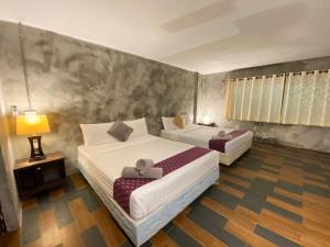 a bedroom with two beds and a table and a lamp at Crescent Bay Resort in Ko Samed