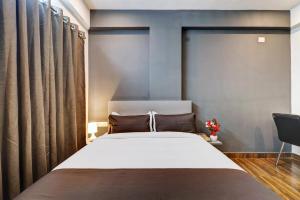 a bedroom with a large bed and curtains at Townhouse Ecity Inn in Bangalore