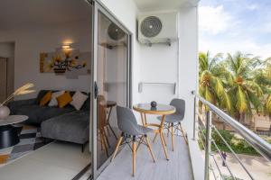 a balcony with a couch and a table and chairs at Tropical Escape Flic en Flac in Flic-en-Flac