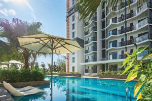 a swimming pool with an umbrella and a building at Timurbay Residences in Kuantan