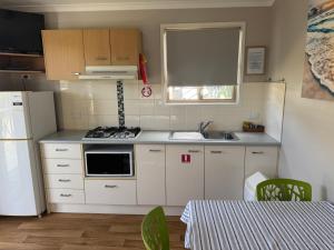 a kitchen with white cabinets and a sink and a refrigerator at Clarence Head Caravan Park in Iluka
