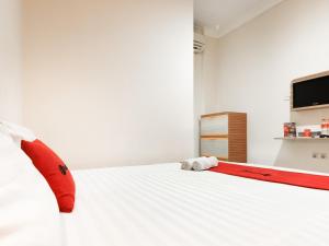 a bedroom with a white bed with a red stretchedvertisement at RedDoorz @ Pandu Raya Bogor in Bogor