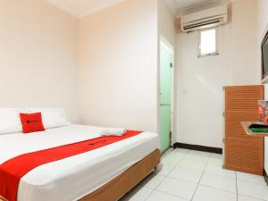 a bedroom with a bed with a red blanket at RedDoorz @ Pandu Raya Bogor in Bogor +18 photos