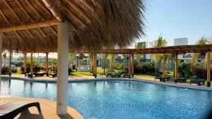 a swimming pool with a straw umbrella and chairs at BellitasHouse Dream Acapulco Lujo y Confort in Acapulco