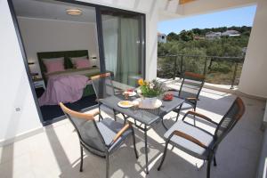a table and chairs on a balcony with a bed at Elegant Villa Punta Sol with hot tube, walk to sea and center in Jezera