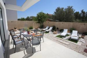 a patio with a table and chairs and a fence at Elegant Villa Punta Sol with hot tube, walk to sea and center in Jezera