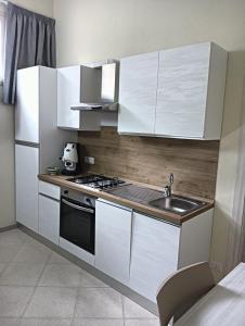 a kitchen with white cabinets and a sink at Cefalù Station House in Cefalù