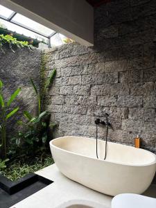 a bath tub in a bathroom with a brick wall at Molog private villa in Ubud +32 photos