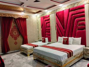 two beds in a room with red curtains at Moon Palace Hotel Lahore in Lahore