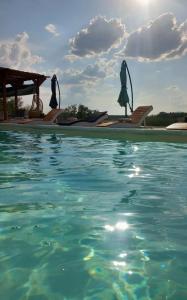 a swimming pool with blue water and two umbrellas at Etno Vila Ognjilo in Kragujevac