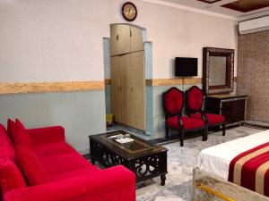 a hotel room with a red couch and a bed at Moon Palace Hotel Lahore in Lahore