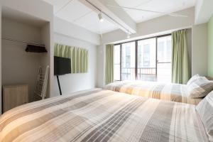 two beds in a bedroom with a tv at Evergreen hotel yotsuya in Tokyo