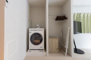 a washing machine in a room next to a bed at Evergreen hotel yotsuya in Tokyo